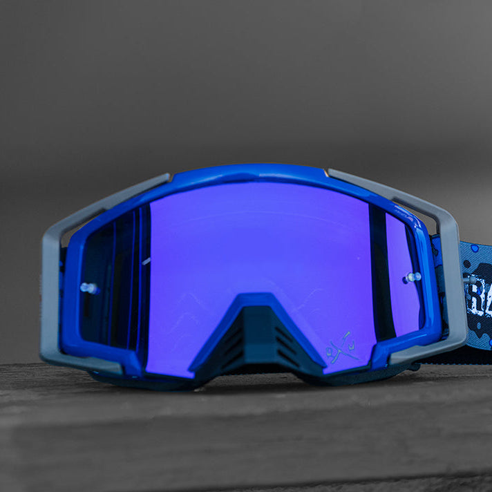 Blue goggles with a branded strap on a wooden surface